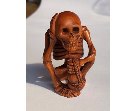 JAPANESE NETSUKE OF A SEATED SKELETON HOLDING A RIBBON TIED BAG
