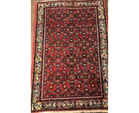 2OTH CENTURY CARPET WITH LOZENGE AND MOTIFS ON A RED GROUND WITHIN A BORDER,FRINGED 160CM X107CM