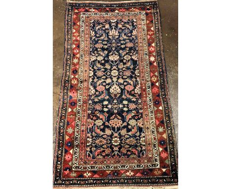 20 TH CENTURY CAUCASIAN CARPET WITH CENTRAL FLORAL MOTIFS ON A BLUE GROUND WITHIN GEOMETRIC PATTERN BORDER 187CMX 99CM