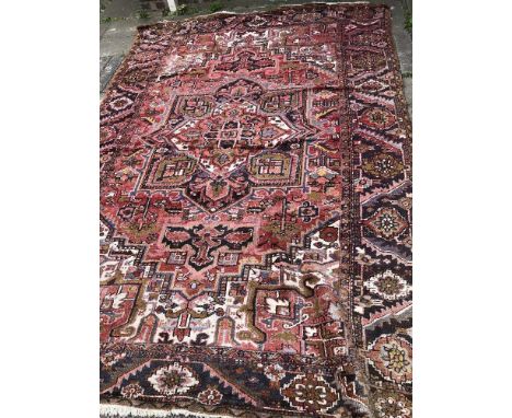 20TH CARPET WITH CENTRAL MEDALLION SUROUNDED BY GEOMETRIC PATTERNS ON A PREDOMINANTLY RED BACKGROUND 244CMX350CM