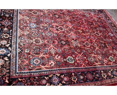 20TH CENTURY CARPET WITH MOTIFS AND PATTERN S ON A RED GROUND WITHIN A BORDER- SLIGHT FADING 293CMX406CM