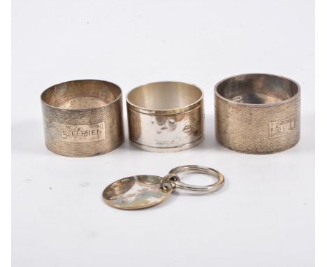 Three silver napkin rings, two engine turned, and a keyring.