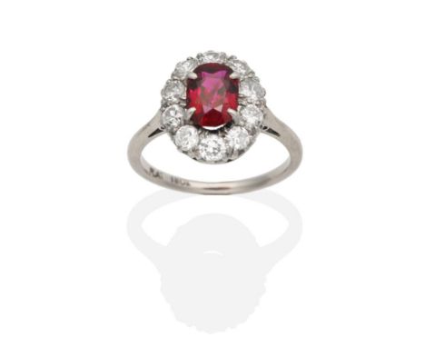 A Ruby and Diamond Cluster Ring, an oval cut ruby within a border of old cut diamonds, to knife edge shoulders, total estimat