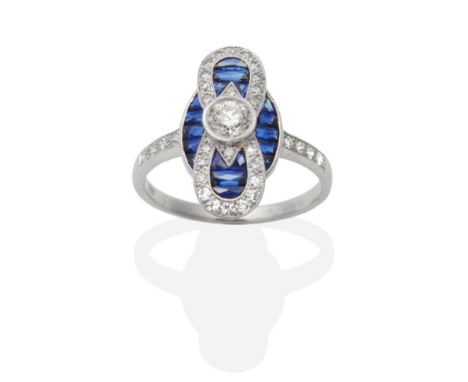 An Art Deco Style Sapphire and Diamond Plaque Ring, an old cut diamond within a plaque of calibré cut sapphires and eight-cut