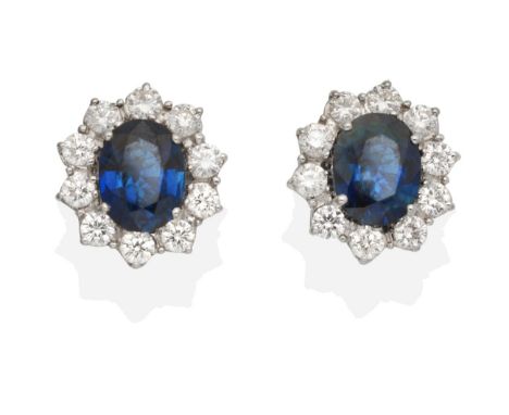 A Pair of Sapphire and Diamond Cluster Earrings, an oval cut sapphire within a border of round brilliant cut diamonds in claw