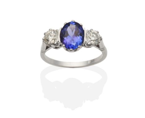 A Tanzanite and Diamond Three Stone Ring, an oval cut tanzanite between two round brilliant cut diamonds in claw settings, to