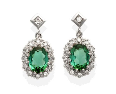 A Pair of Green Tourmaline and Diamond Cluster Earrings, an eight-cut diamond in a square setting suspends an oval cut green 