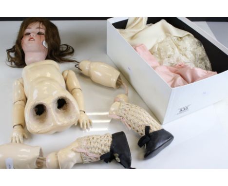 A vintage doll with bisque head and composite body together with a quantity of clothing. 