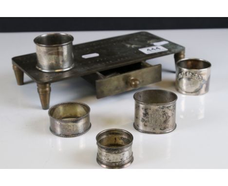 An antique silver plated teapot on tilt stand together with four napkin rings and a brass cribbage board. 