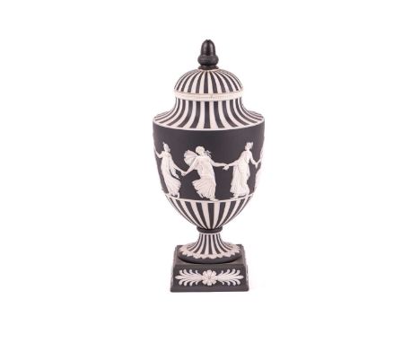 A Wedgwood 'Dancing Hours' black basalt pedestal urn, the cover with acorn finial over a black and white fluted decoration, a
