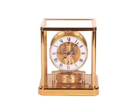 A Jaeger LeCoultre gilt brass Atmos clock, with brass framed glass panels, the white chapter ring with Roman numerals, the mo