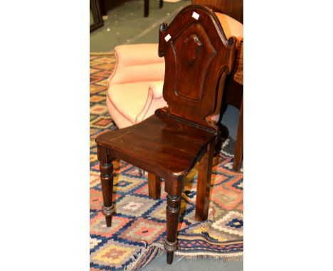 A mahogany hall chair, first half 19th century, the shaped shield back with central cartouche 