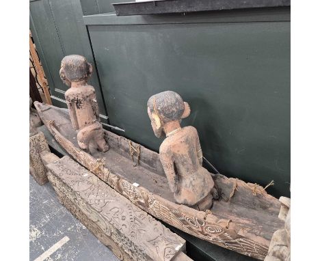 An Indonesian carved canoe with an alligator head and two carved oarsmen. 