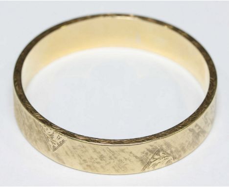 A 14ct gold engraved stiff bangle, decorated with scrolls and a textured ground. Stamped .585. 27.9 grams.