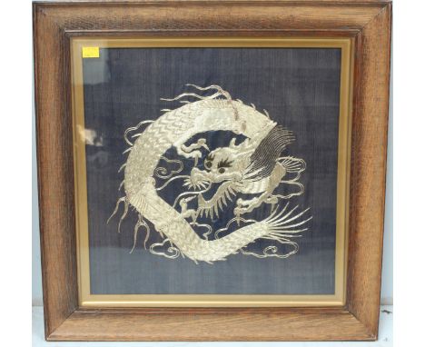 A Chinese framed silk panel depicting an oriental dragon in gold stitching. 53 x 54cm.