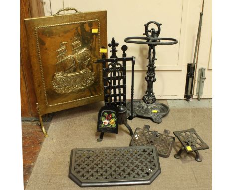 An embossed brass fire screen, together with cast iron stick stand, a set of fire tools and a trivet.