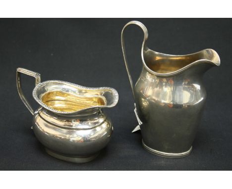 An Edwardian silver helmet shaped cream jug, hallmarked London 1908 together with another small cream jug with gadrooned rim,