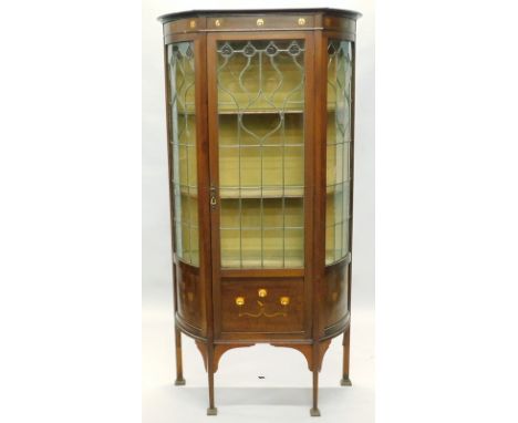 A late 19th/early 20thC mahogany display cabinet in the manner of Liberty, inlaid in copper and pewter, the top with bowed si