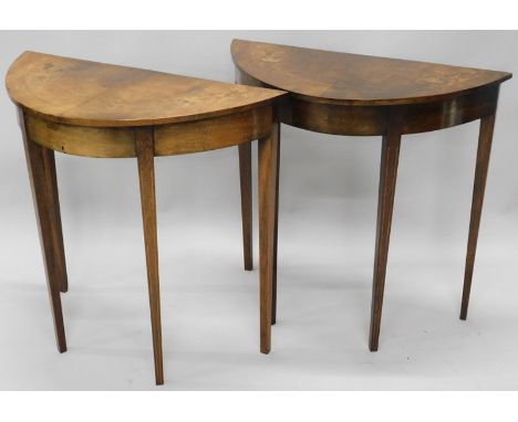 A pair of mahogany and marquetry console tables, each with a demi-lune shaped top, decorated with leaves etc., on square tape