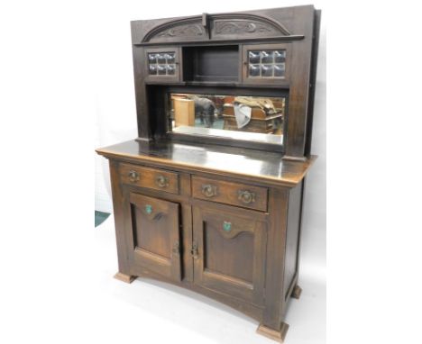 A late 19th/early 20thC ebonised oak Art Nouveau style sideboard, in the manner of Liberty, the raised back with two leaded g