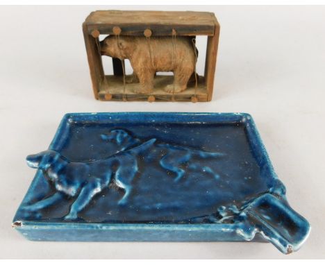 An unusual Black Forest type figure of a bear, in a pine case or cage, 9cm wide and a blue enamel ashtray cast with two gun d