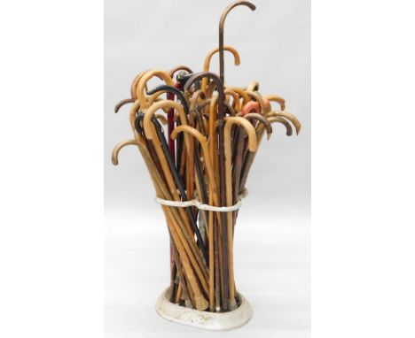 A large quantity of walking sticks and a painted cast iron stick stand