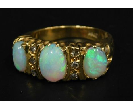 An opal and diamond set dress ring, with three opals and two rows of three illusion set diamonds, yellow metal stamped 18K, 6