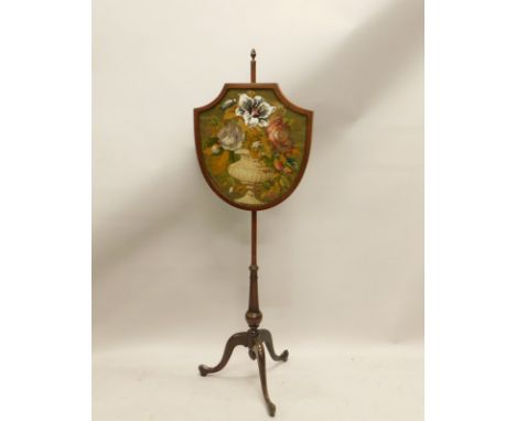 A mahogany pole screen, the shield shaped banner inset with a woolwork, plushwork and beaded panel, on turned column and trip