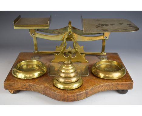 Large Victorian brass and oak parcel scales with brass plaques to base giving parcel and letter rates and with seven weights,