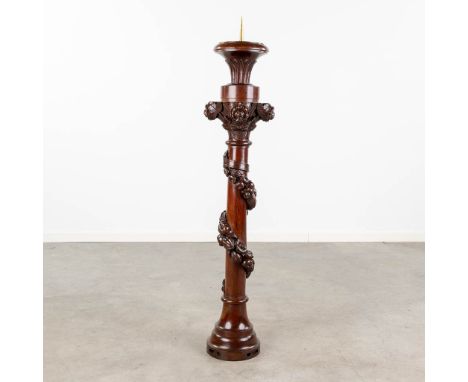 A large candlestick made of sculptured wood and decorated with flowers. Probably made of mahogany.  Dimensions: (H:128 cm)