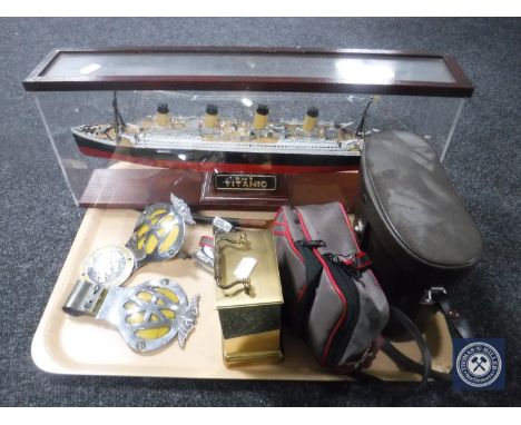 A tray containing wooden model of the Titanic in display case, brass carriage clock, AA badges, set of cased binoculars, pipe