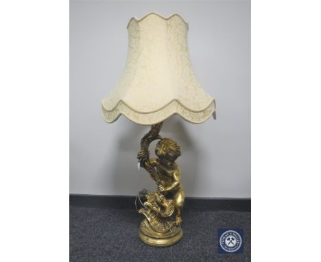A gilt table lamp in the form of a cherub, with shade 