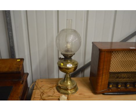 A brass oil lamp with glass shade decorated with flowers 