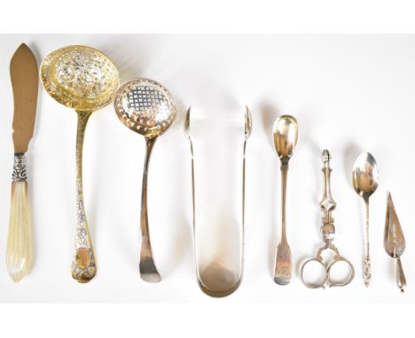 Georgian and later hallmarked silver items to include two sifter ladles, sugar nips, fiddle pattern sugar tongs, novelty book