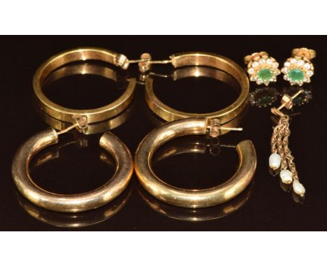 Two pairs of 9ct gold hoop earrings (11.2g), a pair of yellow metal earrings set with emeralds surrounded by diamonds and a s