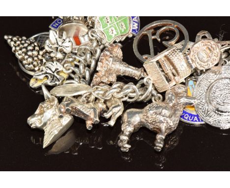 A silver charm bracelet with over 38 silver charms including dogs, motorbike, shamrock, enamel St Christopher, 'Isle of Wight