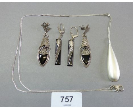 Two pairs of black enamel earrings and a white metal pendant 