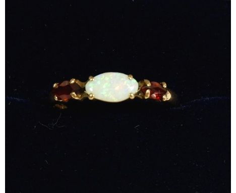 A 9 carat gold ring set opal flanked by two garnets, size N to O, 1.1g 