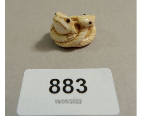 A Japanese Meiji period ivory small netsuke in form of a snake coiled around a frog, signed, 2.3cm wide 