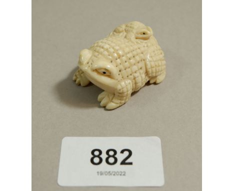 A Japanese ivory Meiji period netsuke of a toad with baby toad to back, signed to base, 4cm long 