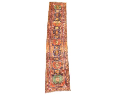 Large Persian Karajeh red ground runner, eight lozenges in green blue and red, decorated with geometric patterns on a red fie