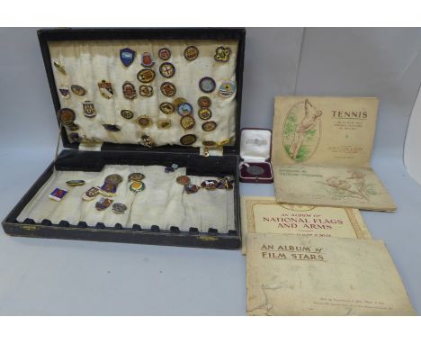A collection of vintage enamel pin badges, a medallion and a collection of cigarette card albums 