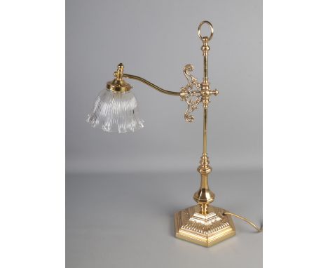 A brass desk lamp with frilled glass shade.  