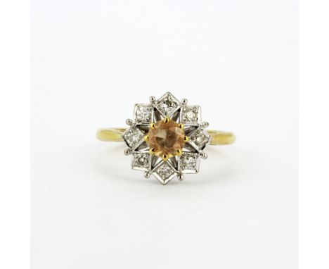 A hallmarked 18ct yellow and white gold ring set with an imperial topaz surrounded by diamonds, (P).