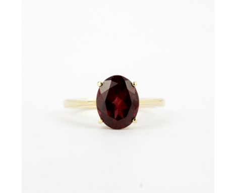 A 14ct yellow gold solitaire ring set with an oval cut garnet, (N.5).