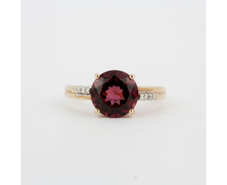 A 14ct rose gold ring set with a round cut garnet and diamond set shoulders, (O).