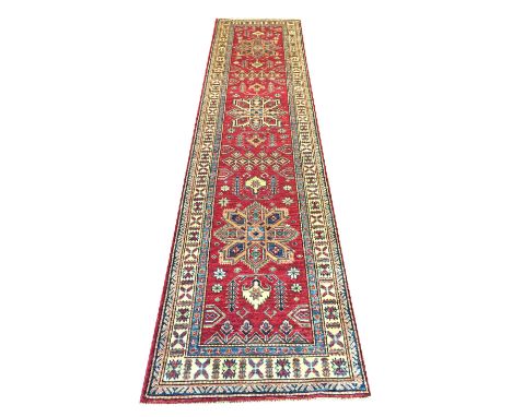 KAZAK RUNNER, 360cm x 83cm, stylised organic medallions within a ruby field within corresponding borders.