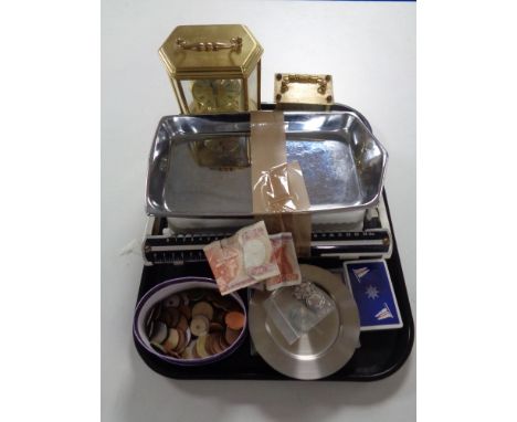 A tray of carriage clocks, foreign coins, bank notes, baby weighing scales etc 
