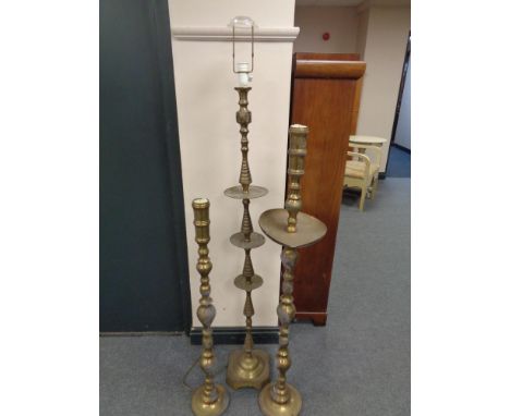 An Indian brass standard lamp together with two similar floor standing candlesticks 
