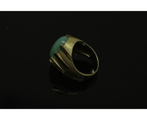 A continental yellow gold ring, the textured shank set with a cabochon apple green jade stone, size N, 10.8g.